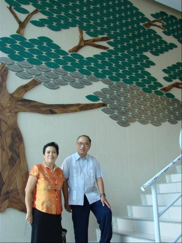 Alumni Affairs Director Jong de la Cruz and Ed Agnir pose in front of the Tree of Life
